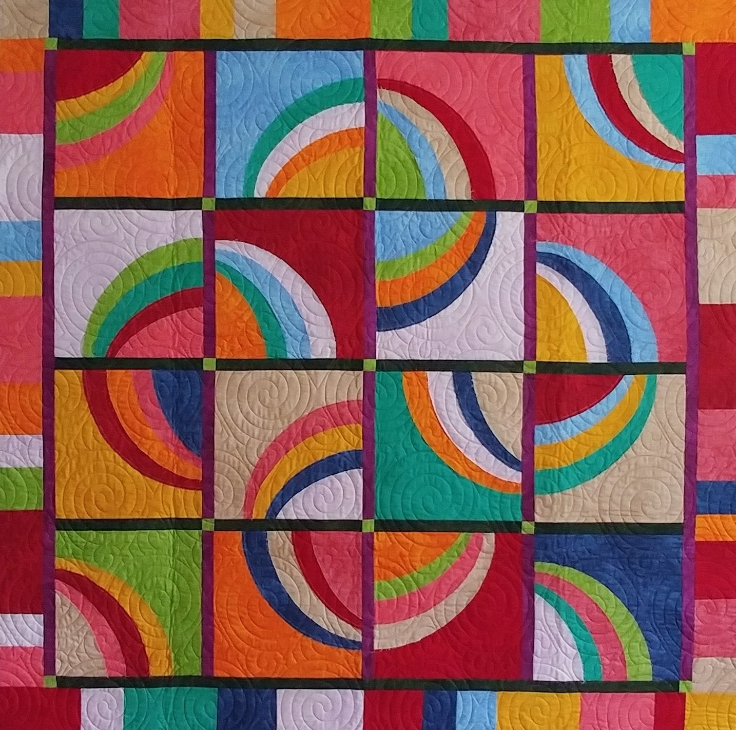 A colorful geometric quilt featuring a 4x4 grid of rainbow arches and curved stripe patterns in red, orange, yellow, green, blue, pink, and white, separated by dark grid lines.